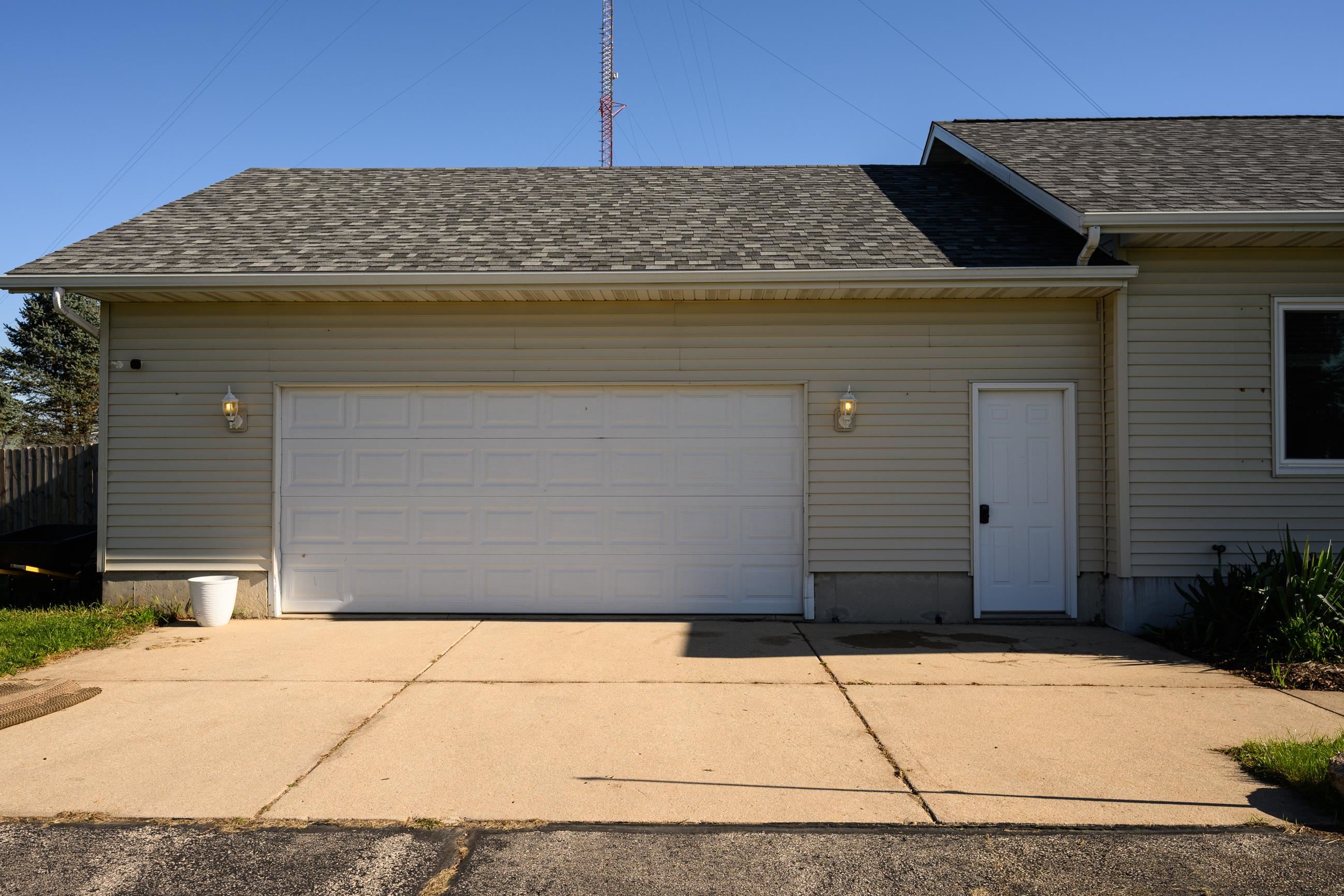 House exterior with a wide white garage door and paved driveway.