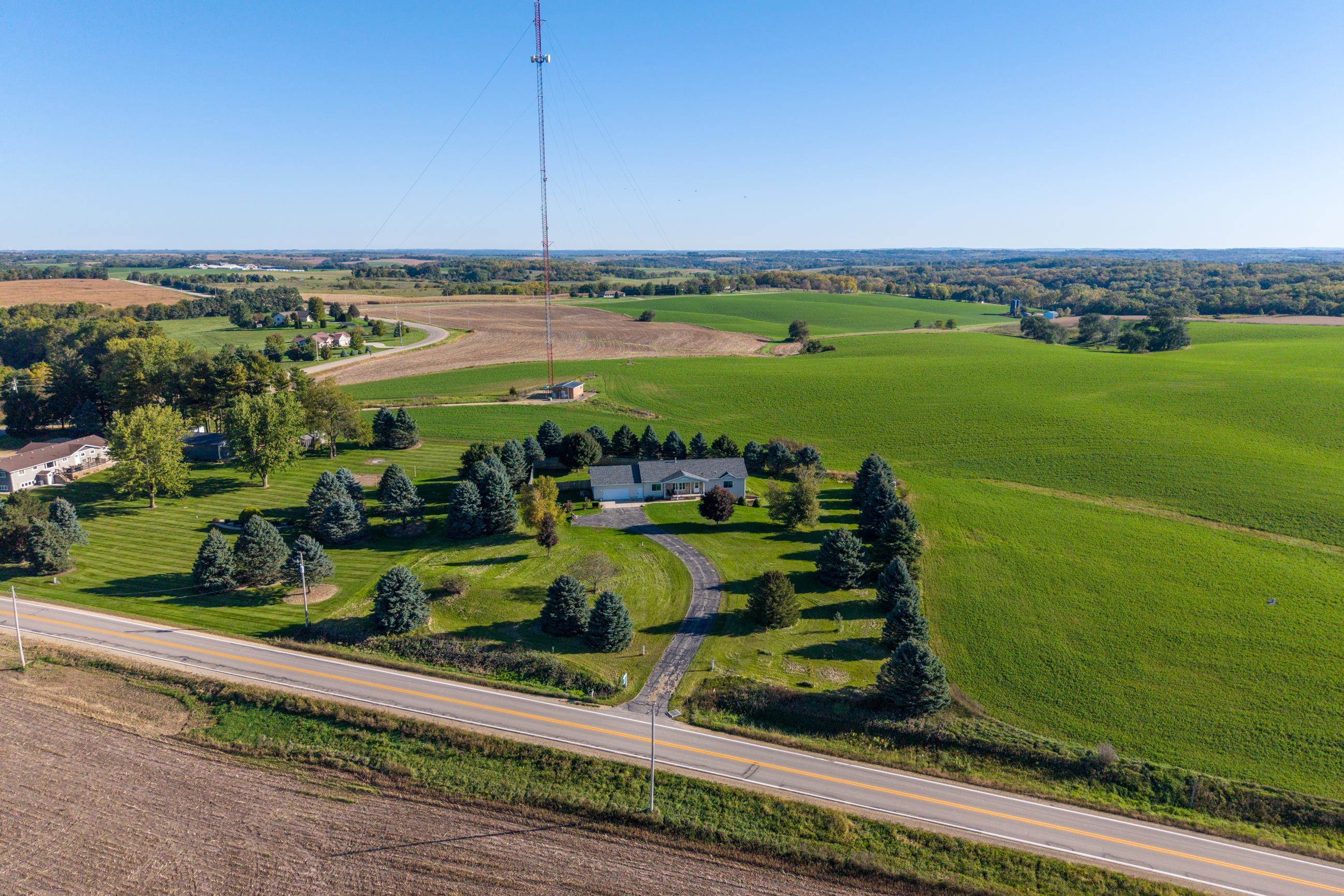 Aerial view of a rural home beside Highway 39, surrounded by trees, fields, and a tall radio tower.