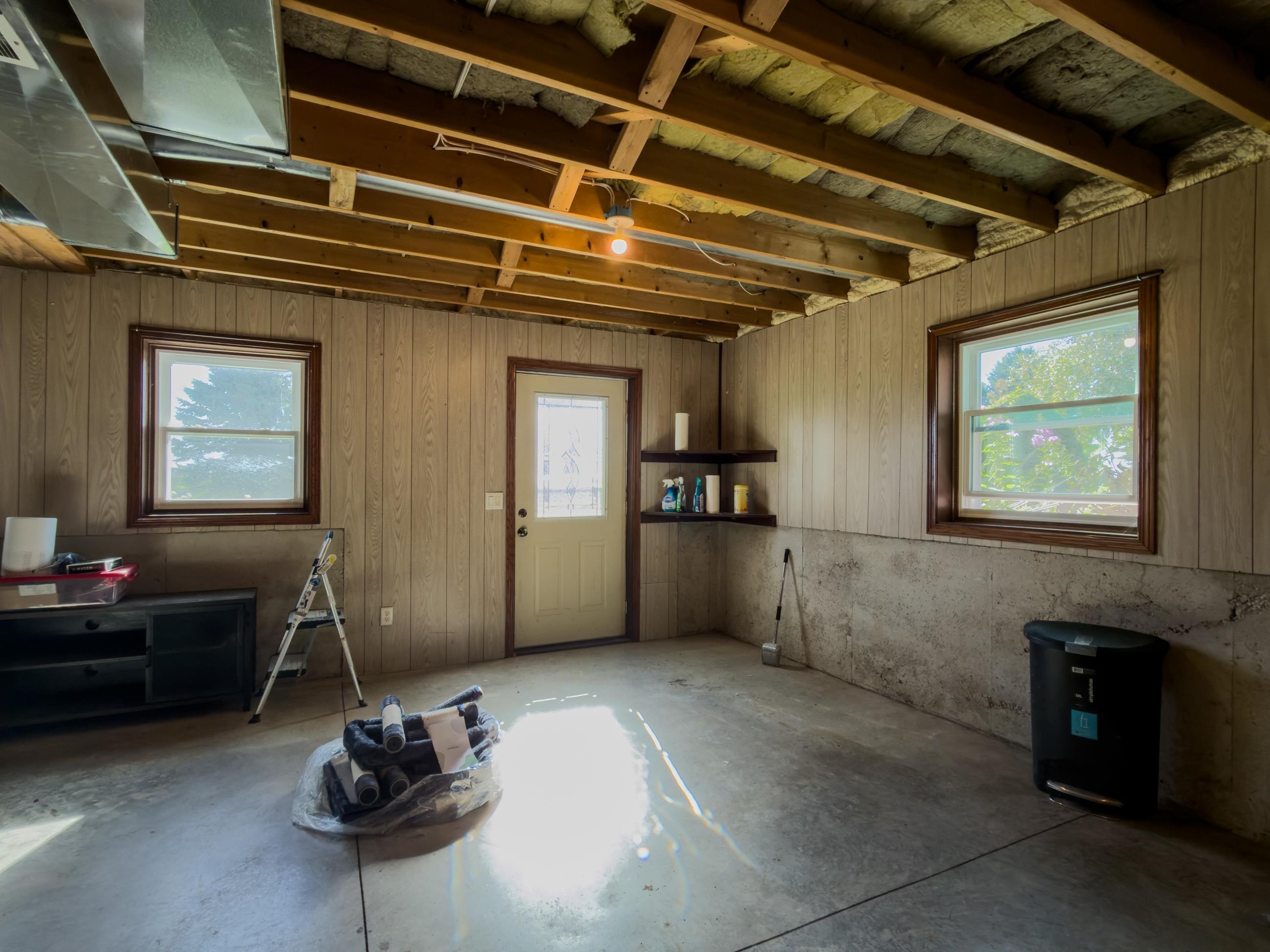 Garage with a concrete floor, exposed insulated ceiling, and windows on two walls.