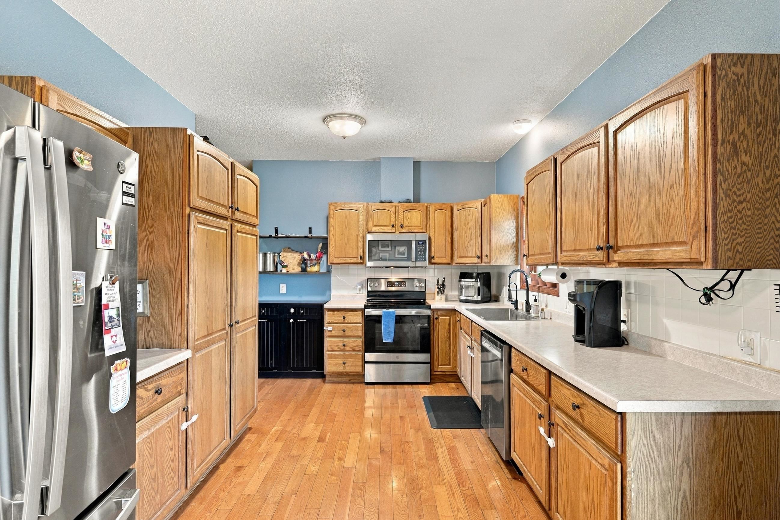 Kitchen with oak cabinets, hardwood floors, stainless appliances, and long counters.