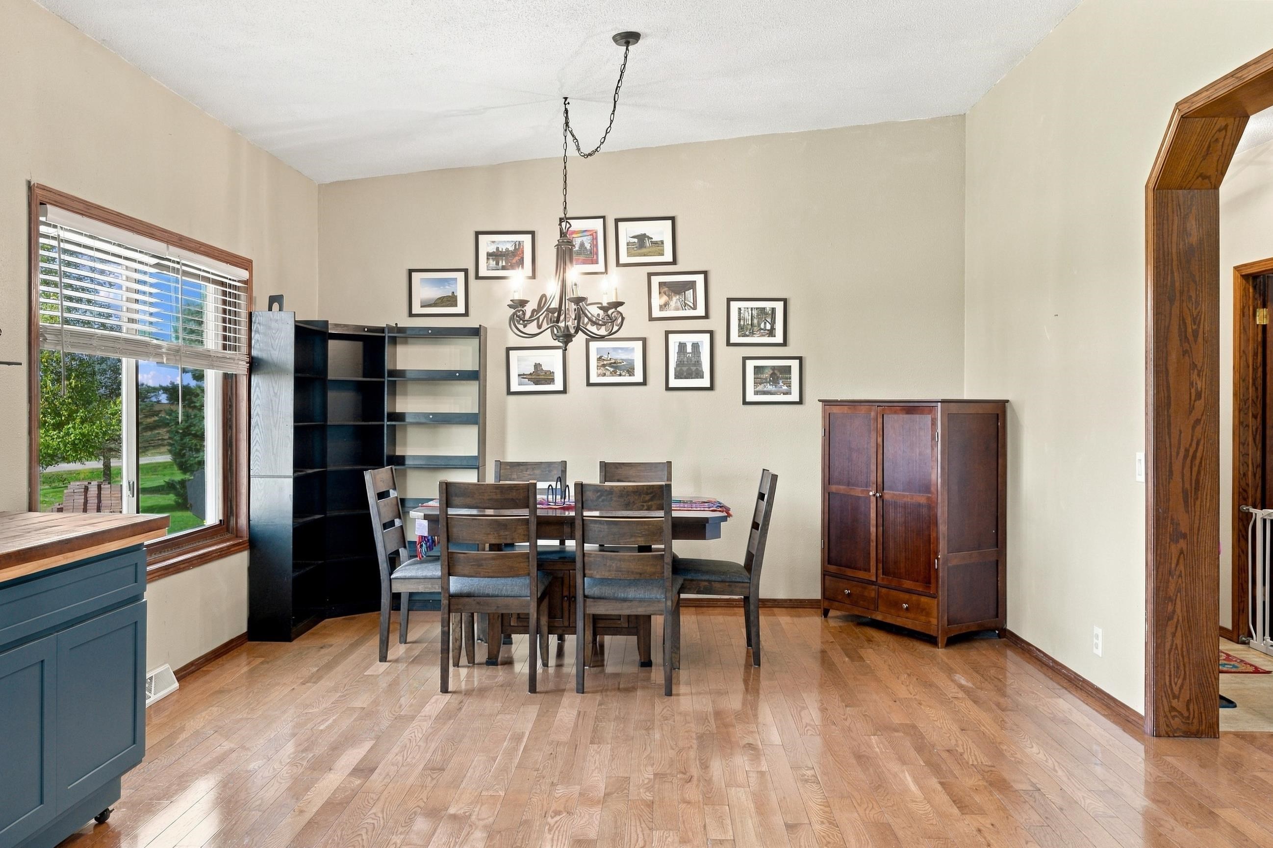 Dining room with a wooden table, dark chairs, hardwood floors, and a chandelier.