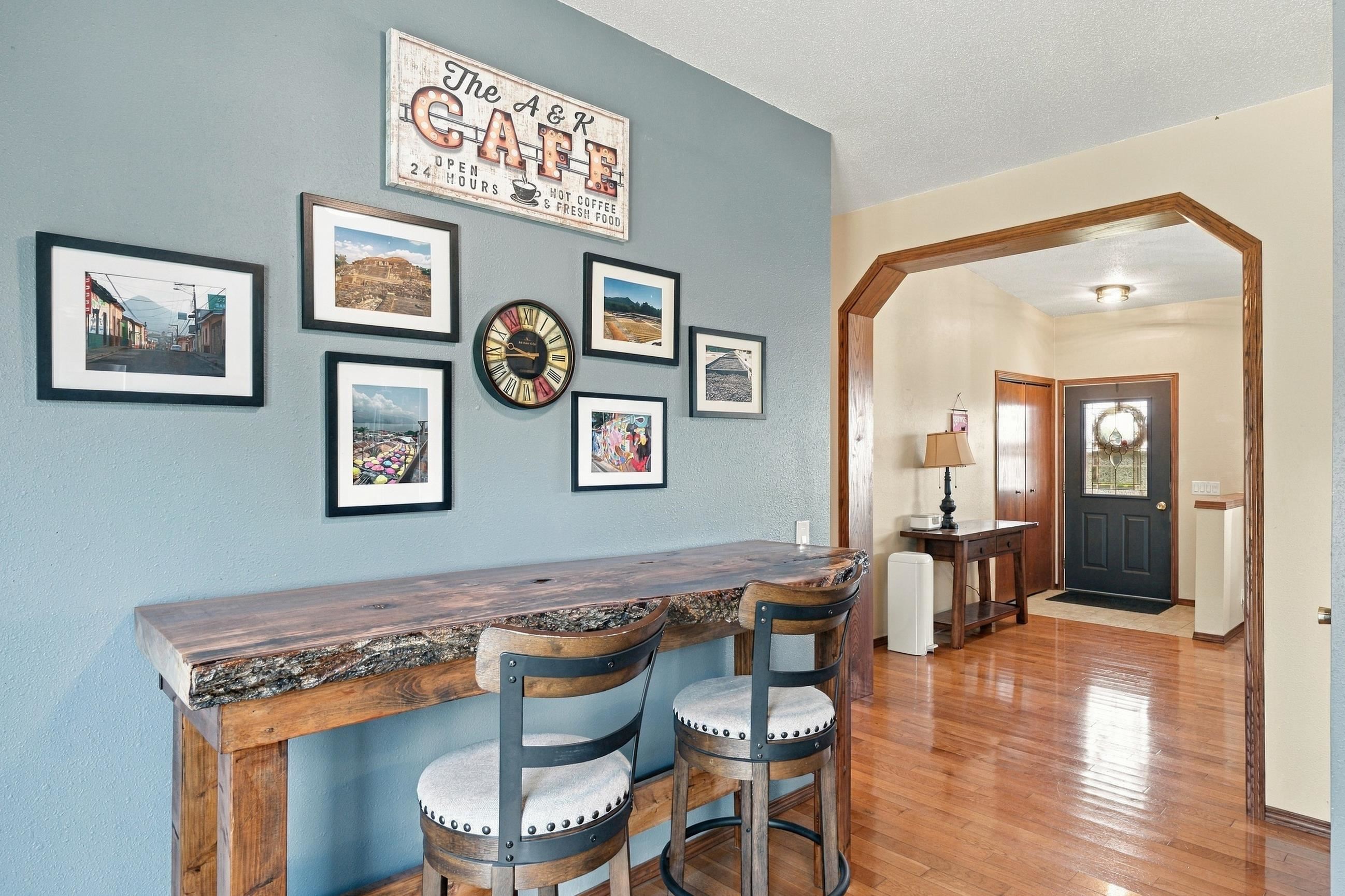 Entryway with a rustic wood counter, stools, and an arched doorway to the front door.