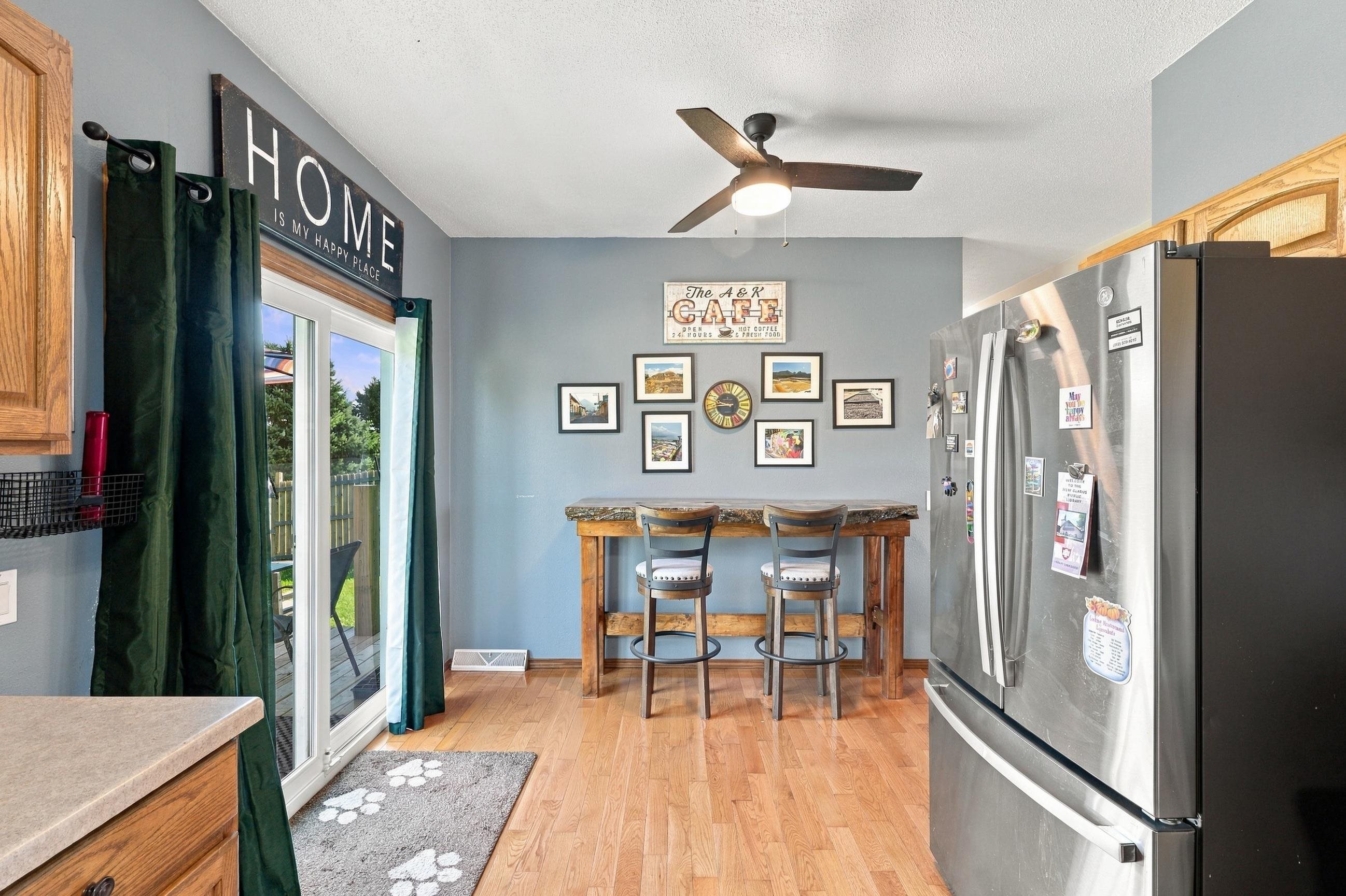 Kitchen with wood cabinets, stainless steel refrigerator, and a breakfast table beside sliding glass doors.