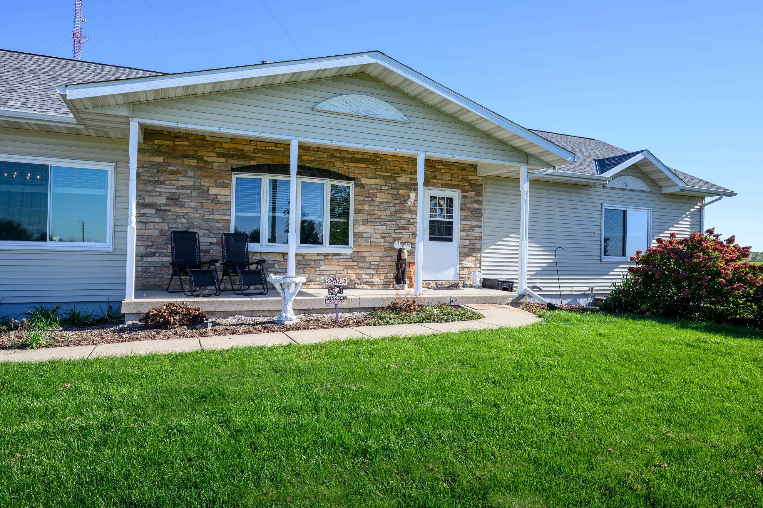 Single-story home with a stone-accented facade, covered porch, and broad green lawn.