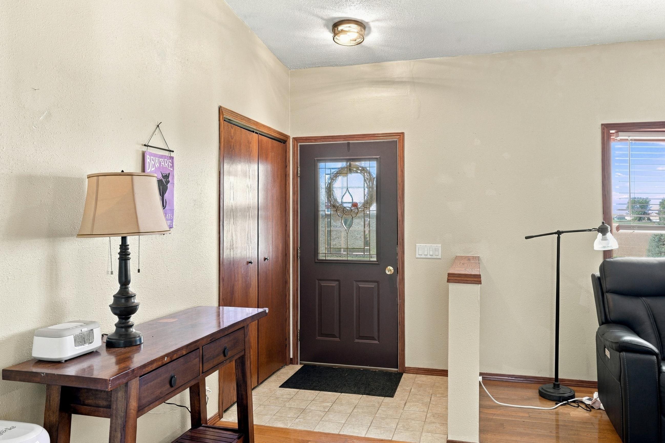 Entryway with a stained-glass front door, wooden console table, and black leather recliner.