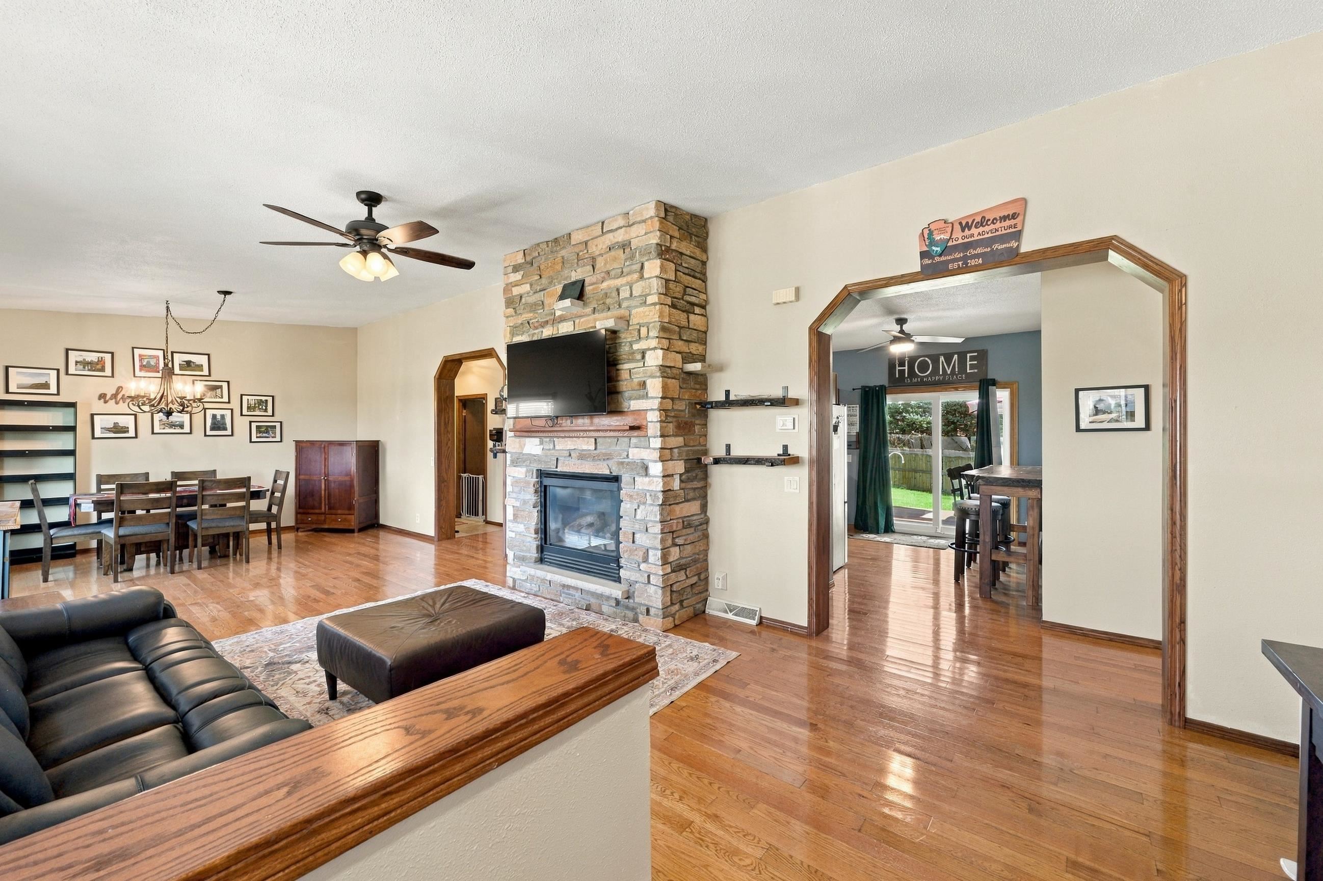Open living and dining area with a stone fireplace, hardwood floors, and an adjoining dining nook.