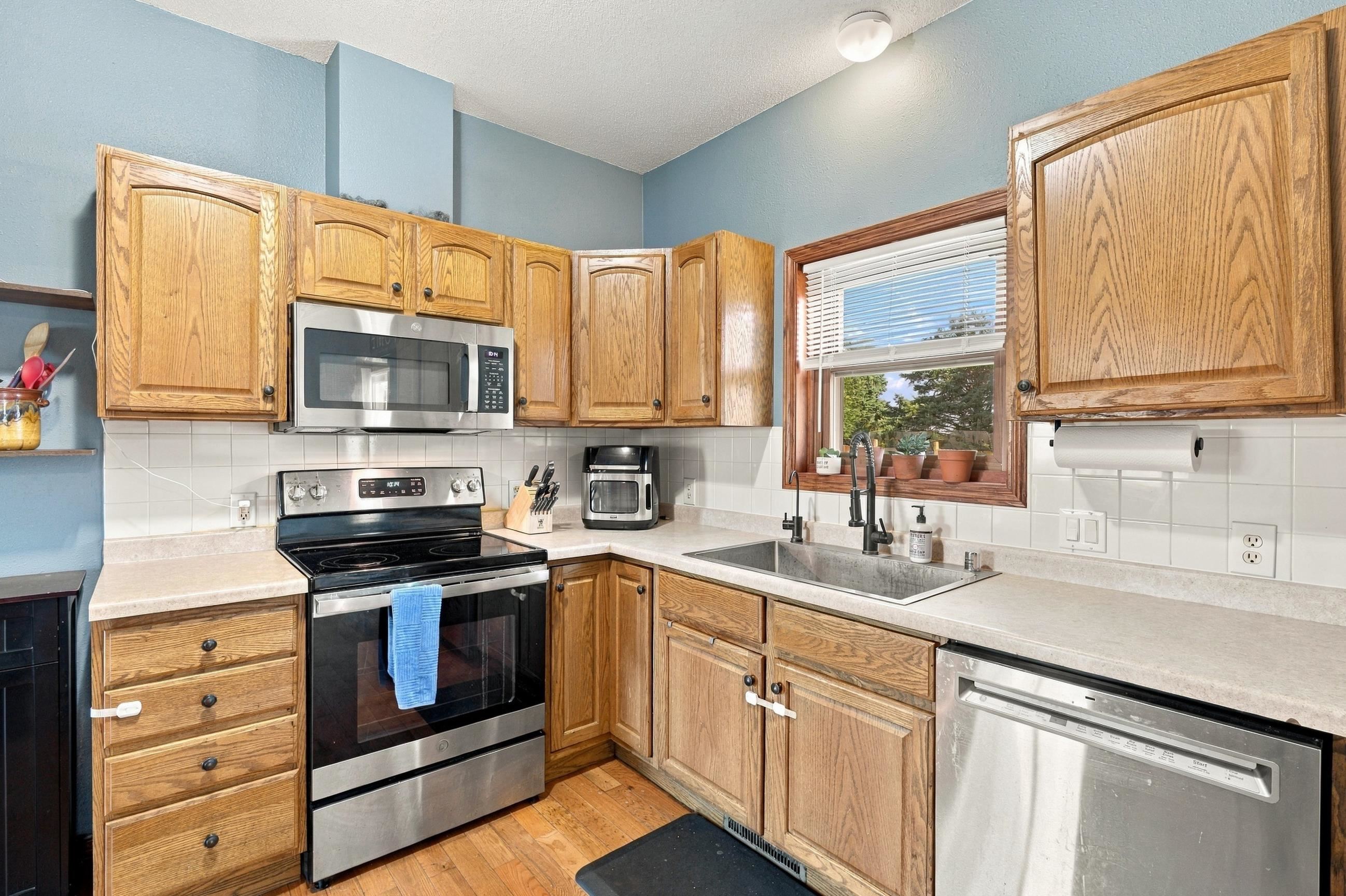 Kitchen with oak cabinets, stainless steel appliances, and a sink beneath a window.