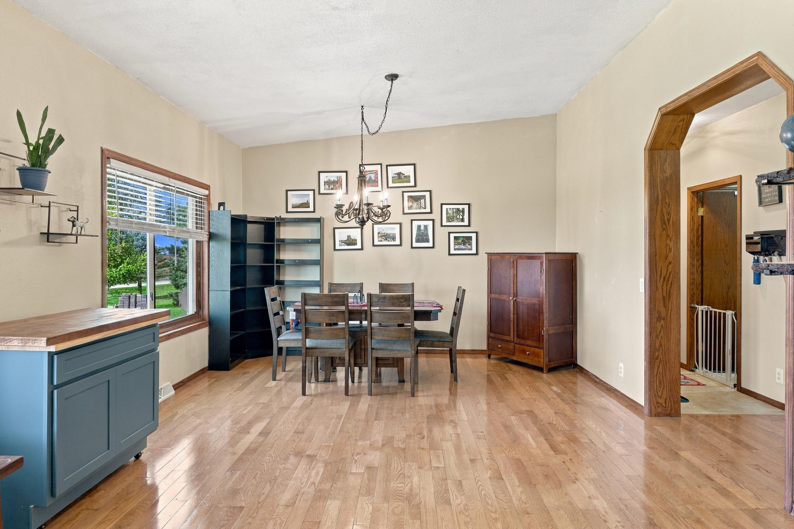 Dining room with a wooden table, framed pictures, and a large window overlooking the yard.