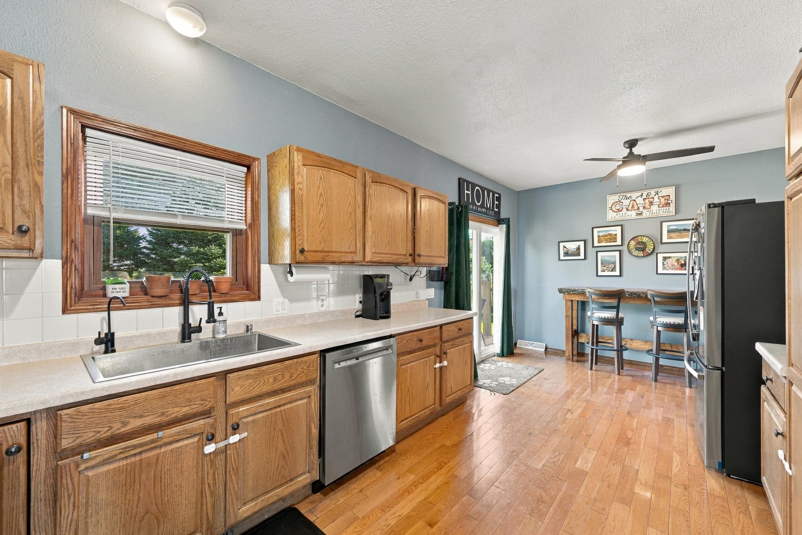 Kitchen with oak cabinets, stainless appliances, and a breakfast bar with two stools.