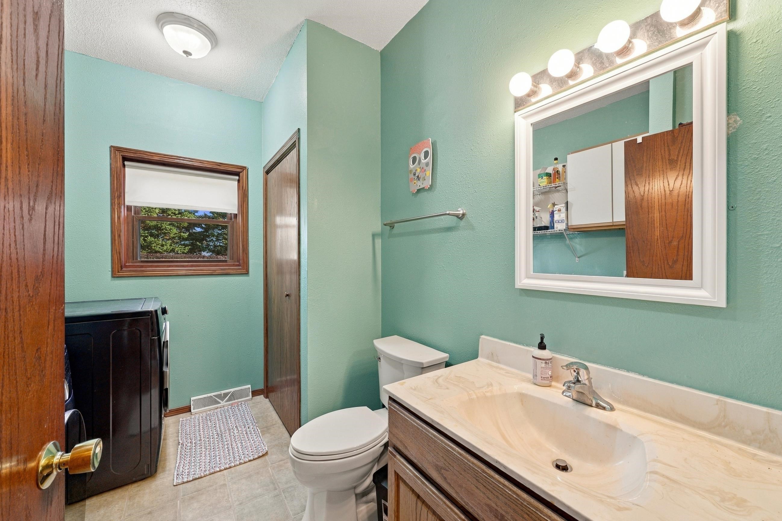 Bathroom with mint-green walls, wood vanity, and a mirrored medicine cabinet.