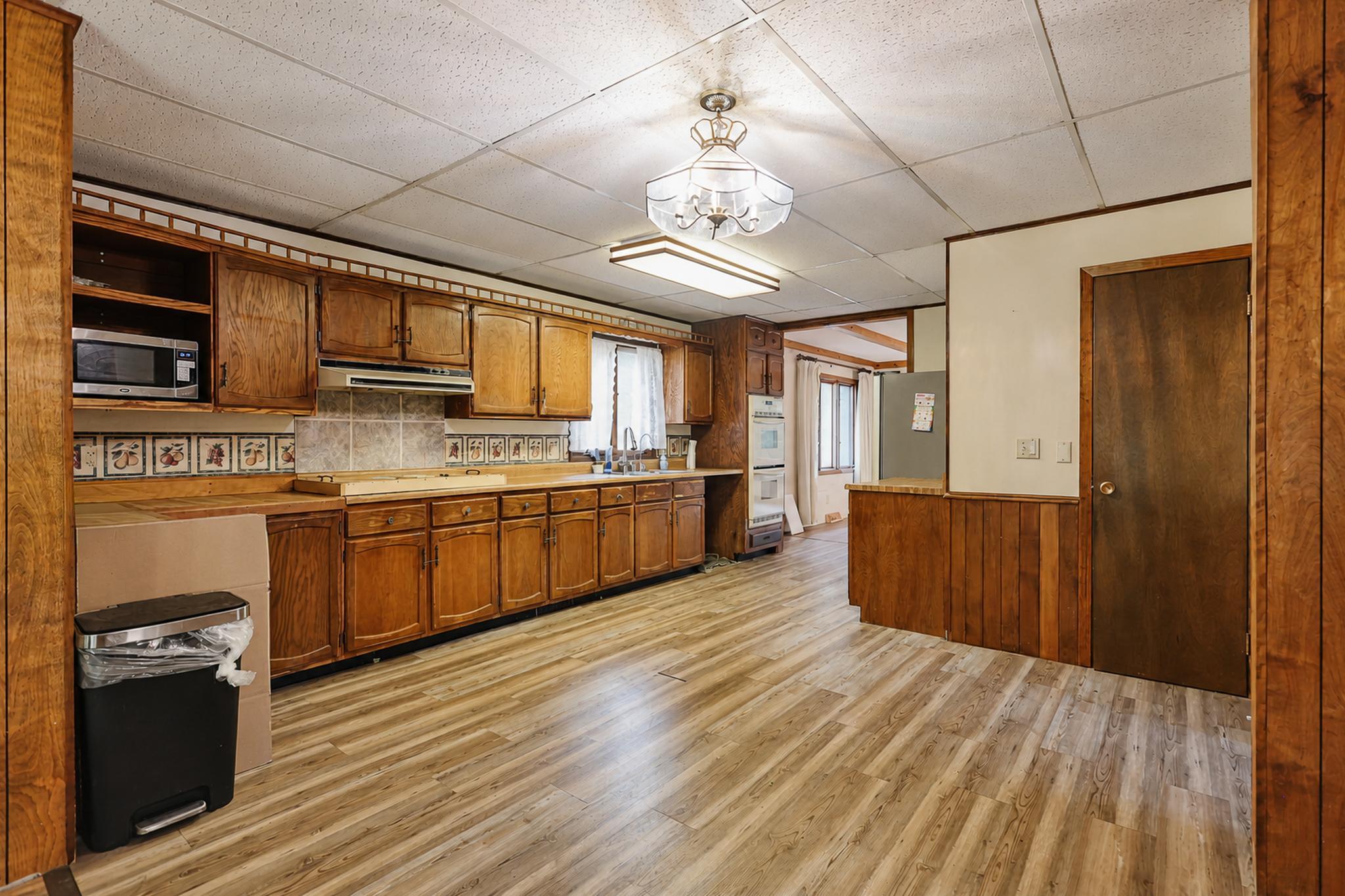 Kitchen with extensive wood cabinetry, a built-in microwave, and light plank flooring.