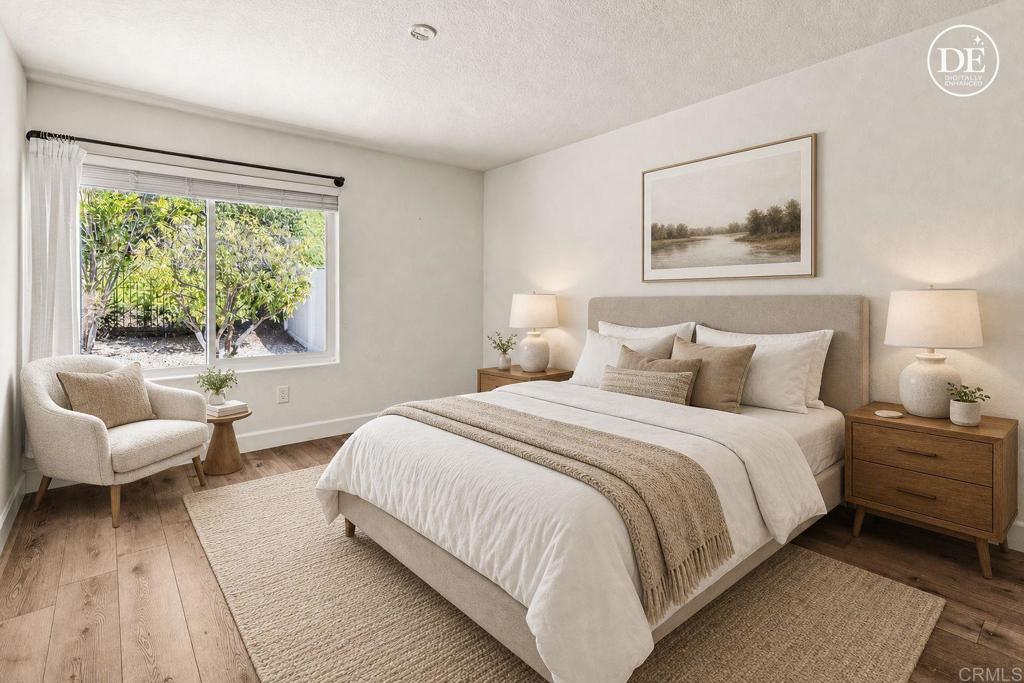 Staged bedroom with a king bed and a window overlooking a leafy garden.