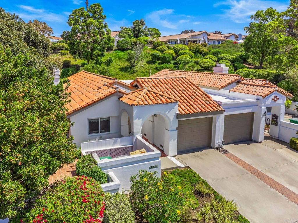 Aerial view of a white stucco home with terracotta roof, arched entry, and double garage.