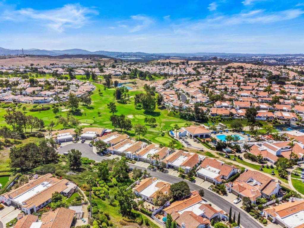 Aerial view of homes bordering a golf course and community pool.
