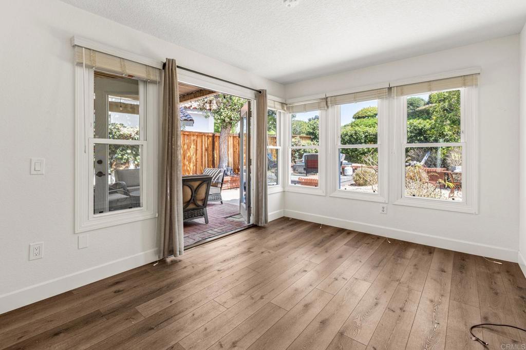 Bright empty room with wood floors, large windows, and a sliding door to the patio.