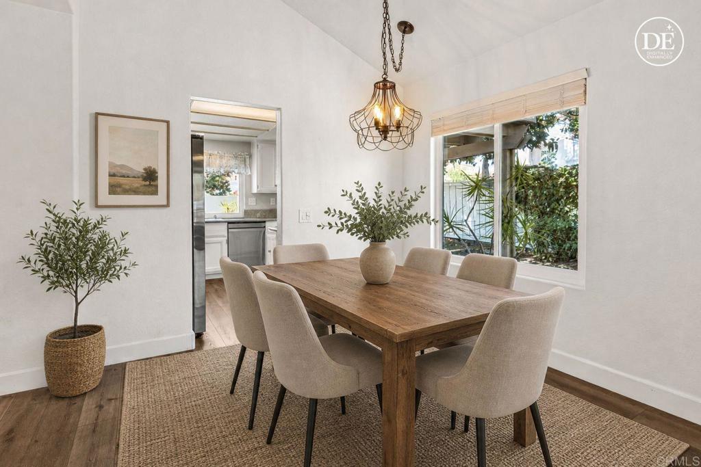 Dining room with a wooden table, upholstered chairs, and a large window overlooking greenery.