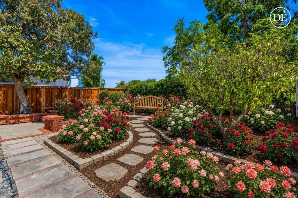 Landscaped backyard garden with stepping-stone paths, flowering roses, and a wooden bench.