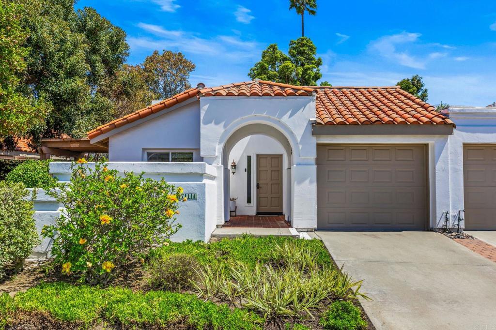 White stucco home with a terracotta tile roof, arched entry, and attached garage.