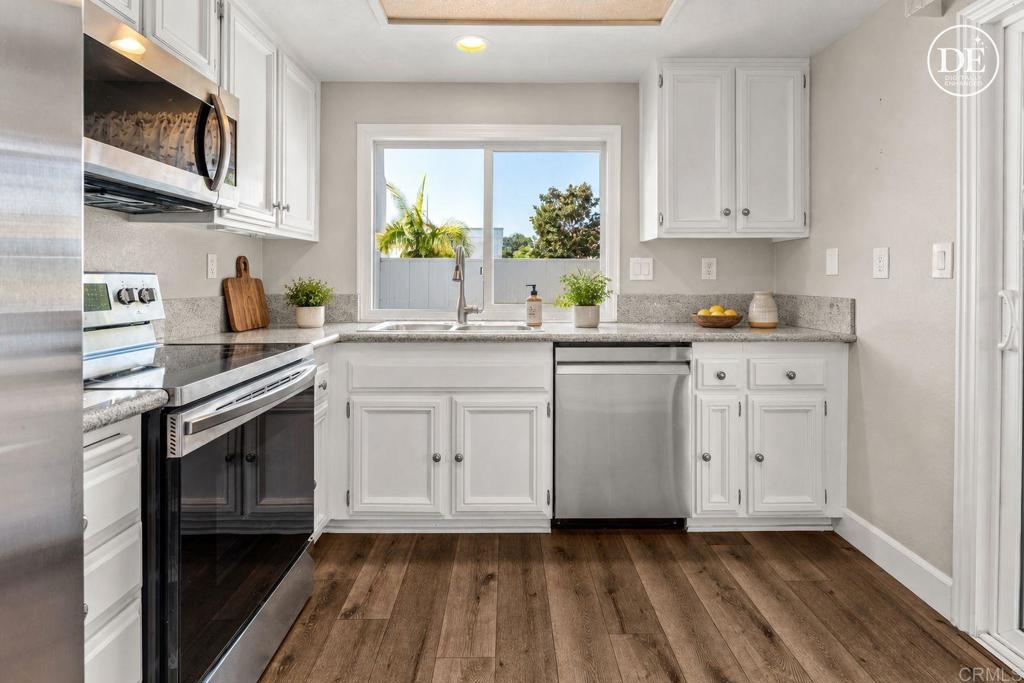 Kitchen with white cabinets, stainless-steel appliances, and a window above the sink.