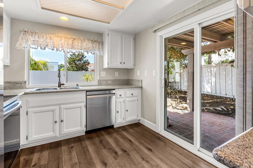 Kitchen with white cabinets and granite counters, opening through sliding glass doors to a brick patio.