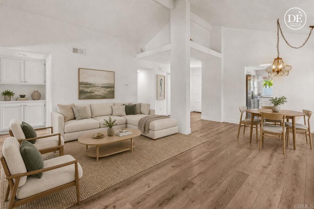 Staged living room with a beige sectional, armchairs, and an open dining area.