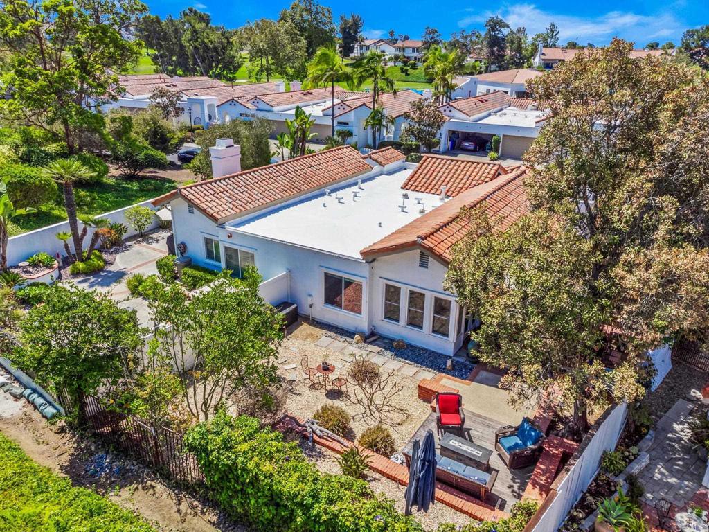 Aerial view of a tile-roofed home and its landscaped backyard patio.