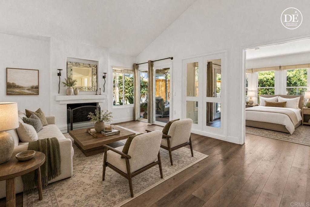 Living room with a fireplace, neutral seating, and glass doors opening toward a patio.