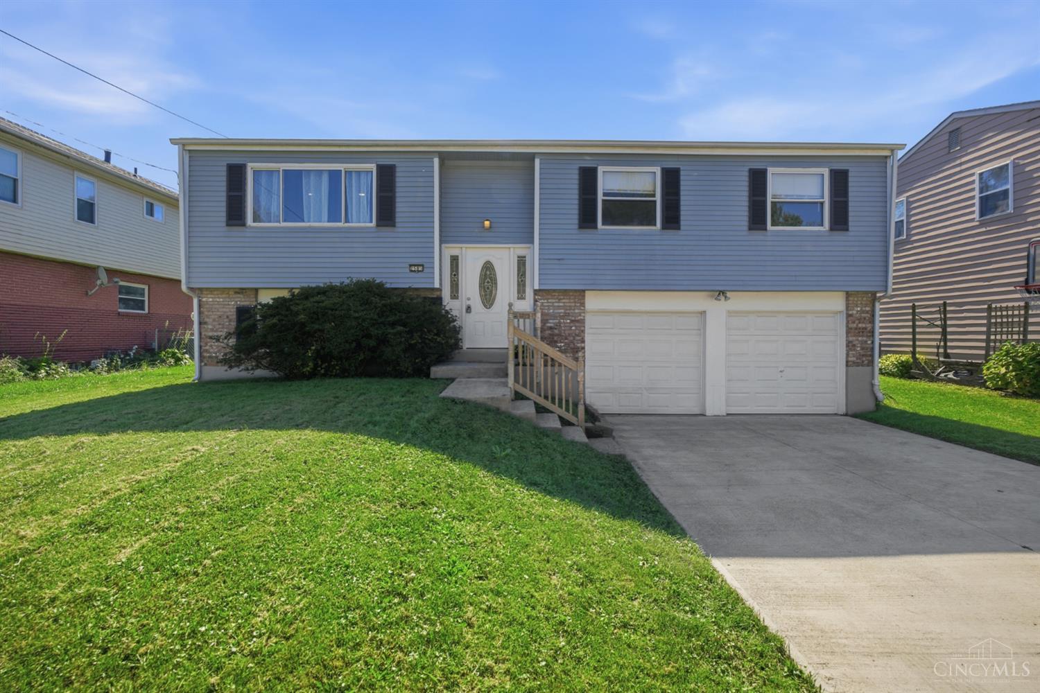 Gray split-level house with a brick lower facade, two-car garage, and broad front lawn.