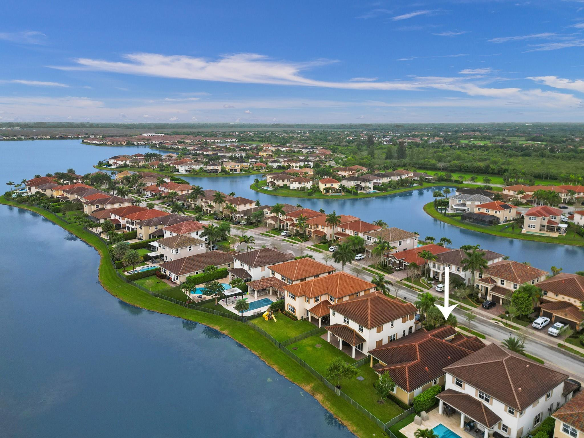 Aerial view of a lakefront neighborhood, with an arrow pointing to the featured two-story home.