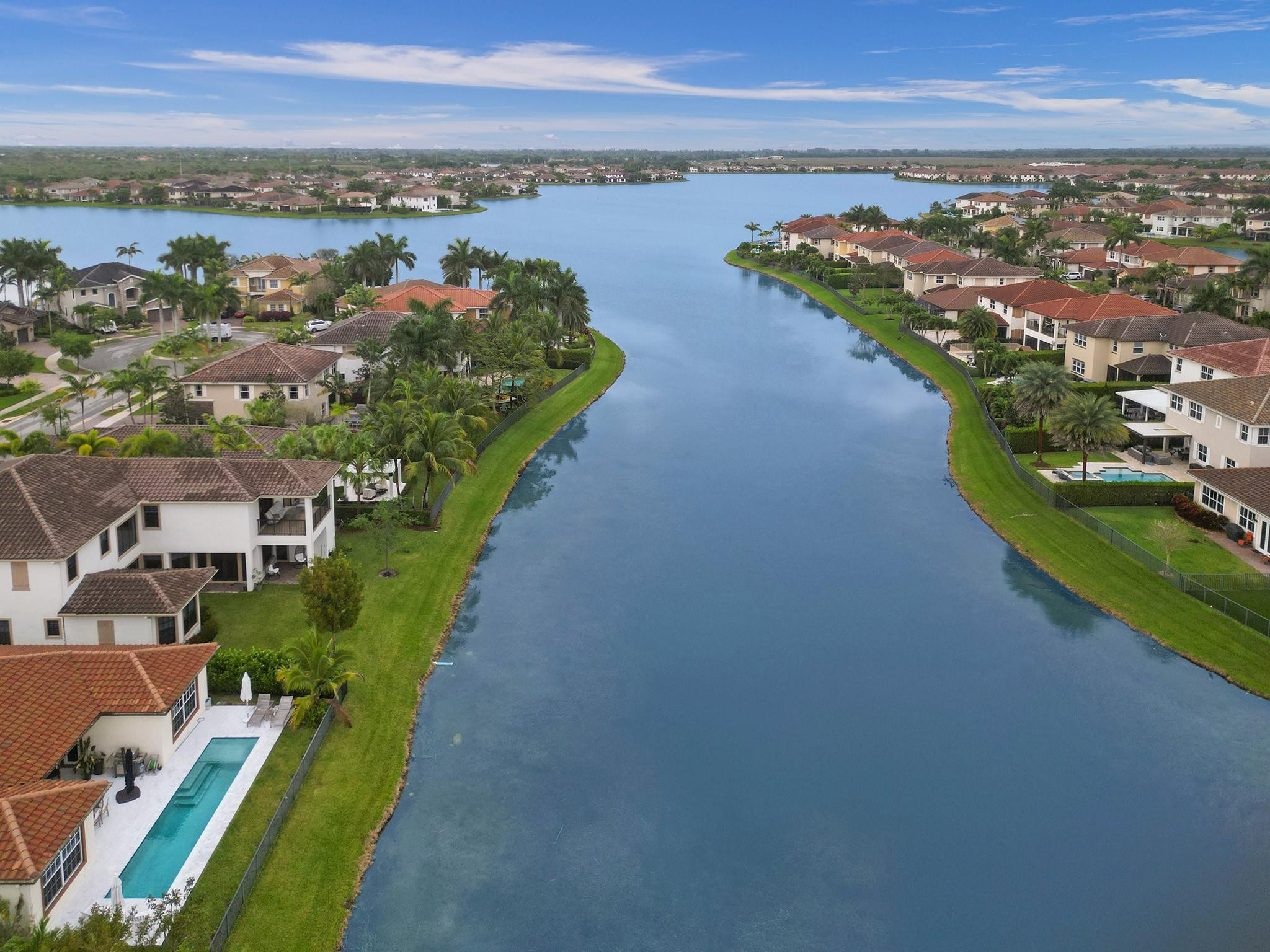 Aerial view of a lake bordered by homes, palm trees, and private pools.