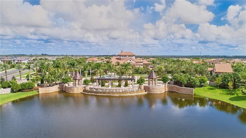 Aerial view of a lakeside community pavilion, palm trees, and homes beyond the water.