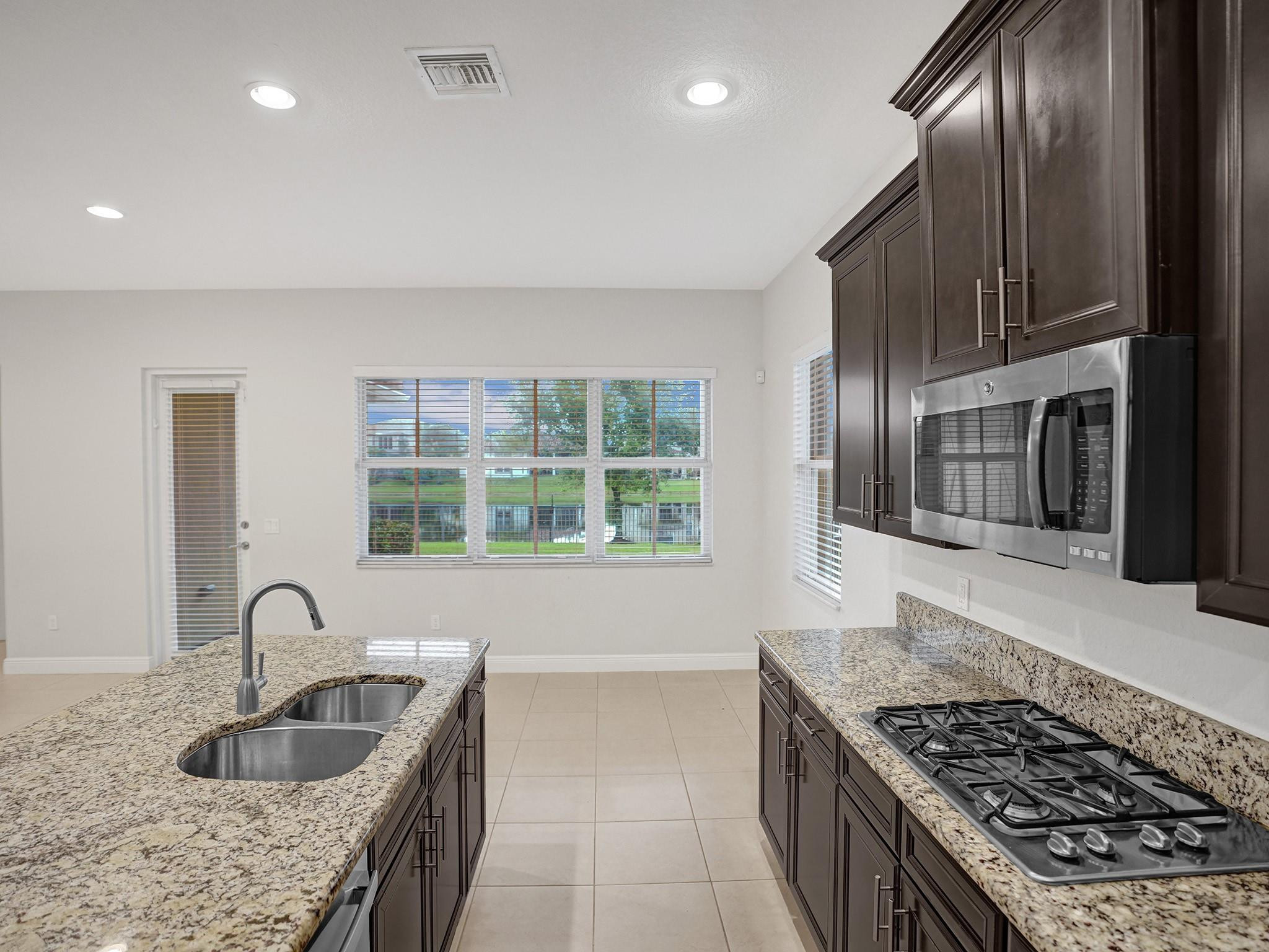 Kitchen with granite counters, dark cabinets, a gas cooktop, and a lake view through the windows.