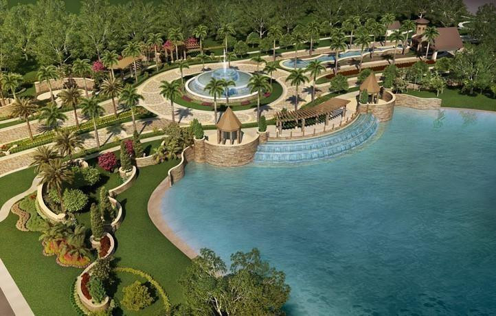 Aerial view of a landscaped lagoon with cascading water, palm-lined paths, and a circular fountain plaza.