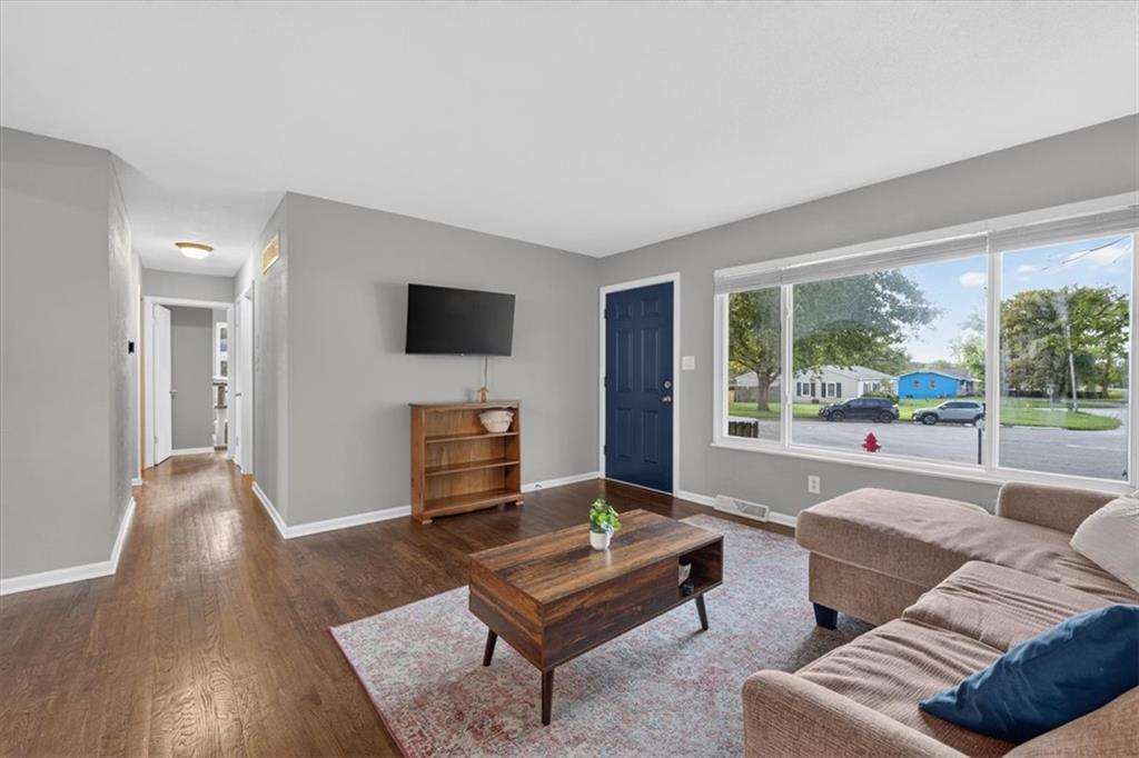 Living room with a tan sectional, wooden coffee table, and large window overlooking the street.