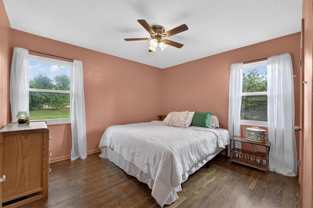 Bedroom with a white bed, peach walls, and two curtained windows.