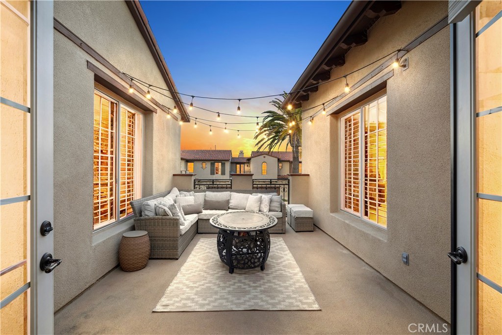 Furnished patio with wicker seating and string lights at dusk.