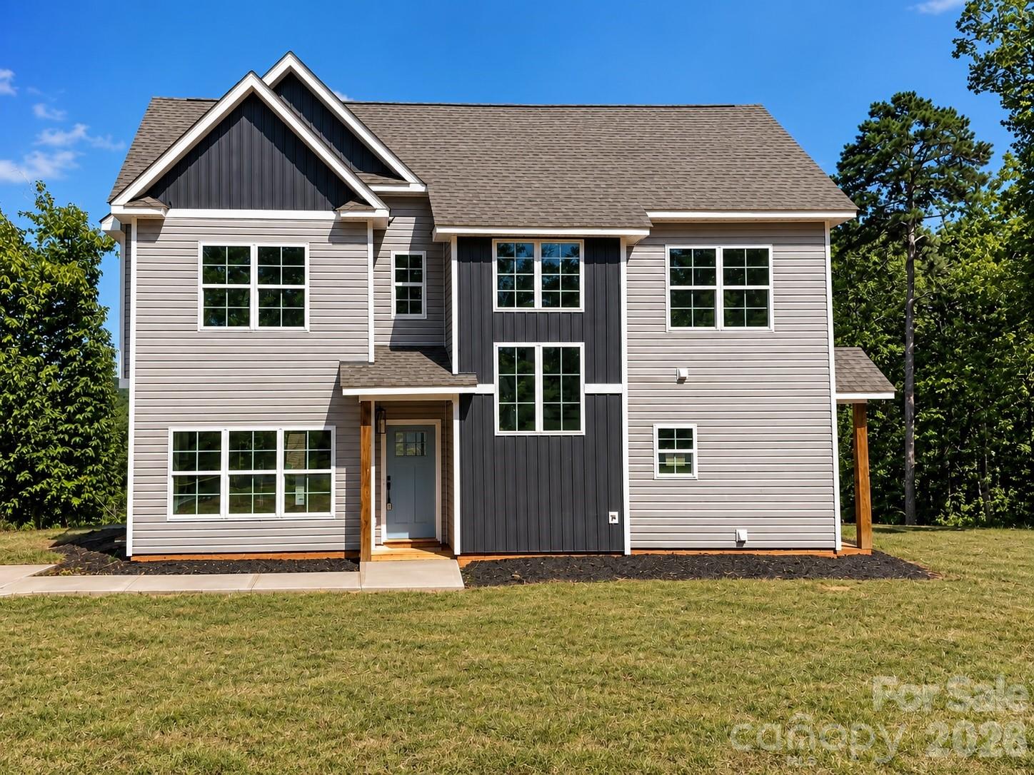 Two-story gray house with dark vertical siding accents, multiple gables, and a covered front entry.