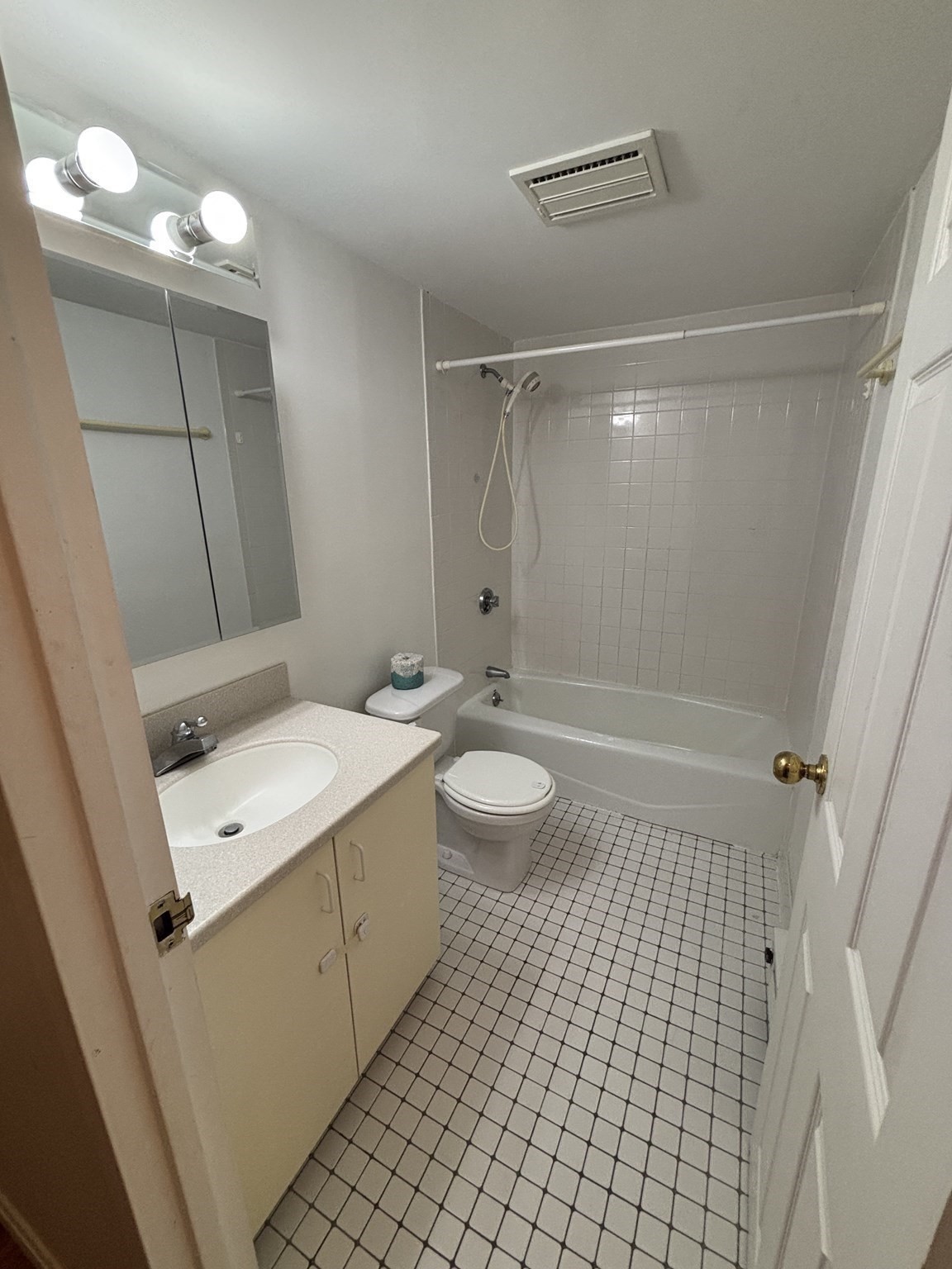 Bathroom with a mirrored vanity, toilet, and white-tiled bathtub and shower.