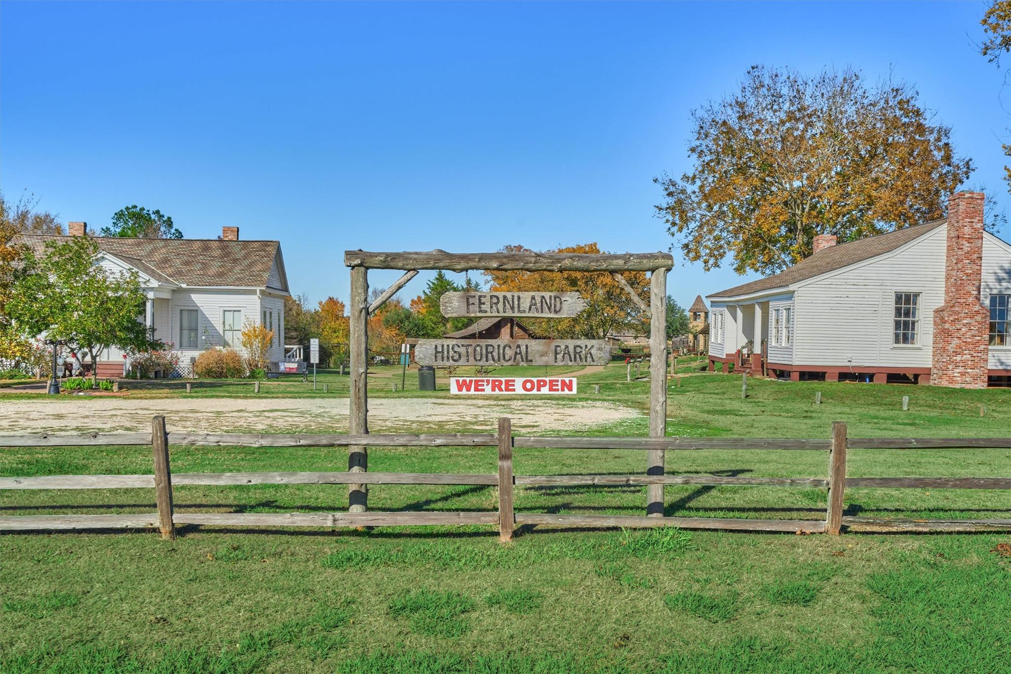 Entrance to Fernland Historical Park, with a wooden sign between historic white buildings.