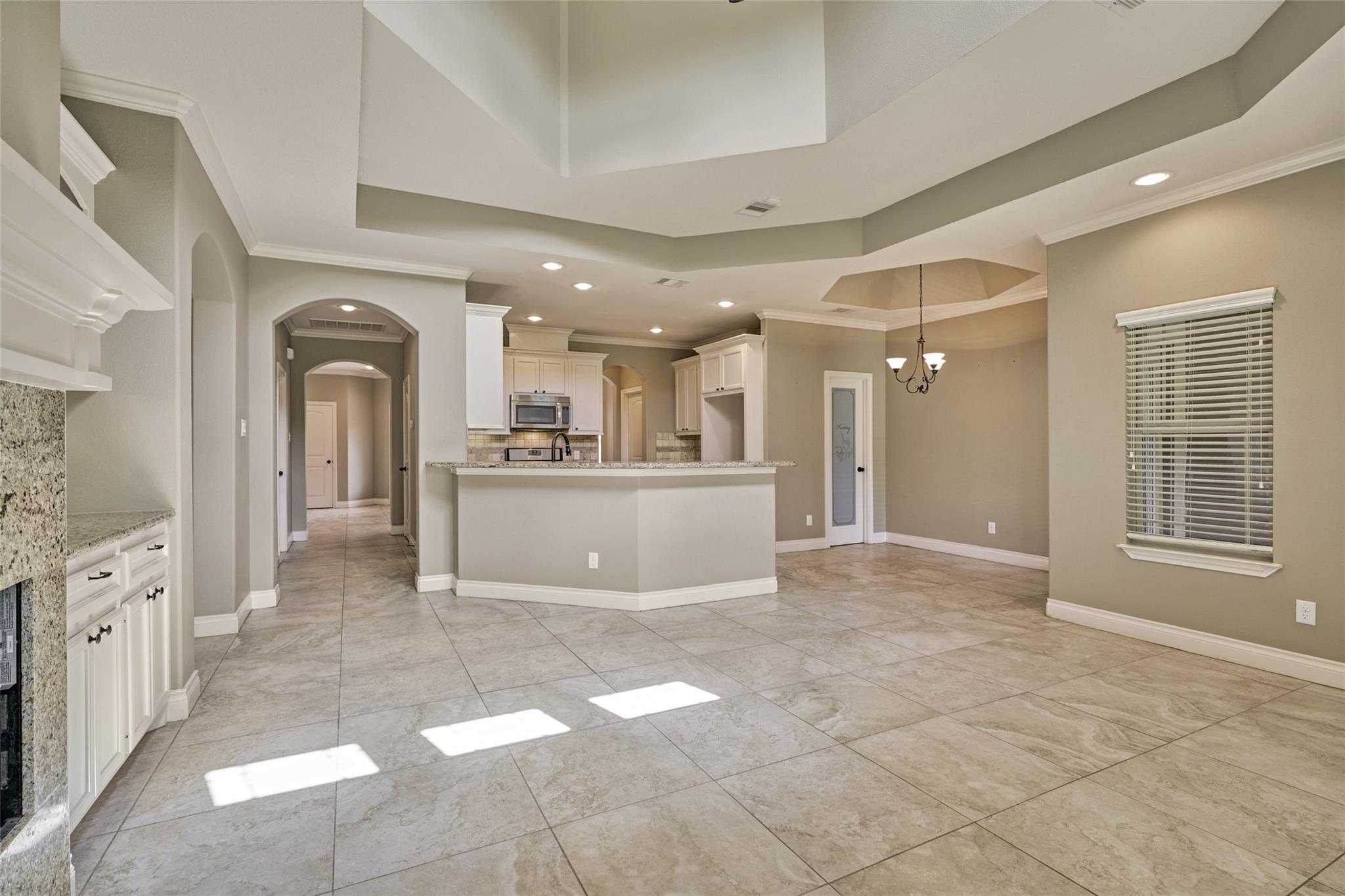 Open-plan kitchen and dining area with a breakfast island, white cabinets, and large tile floors.