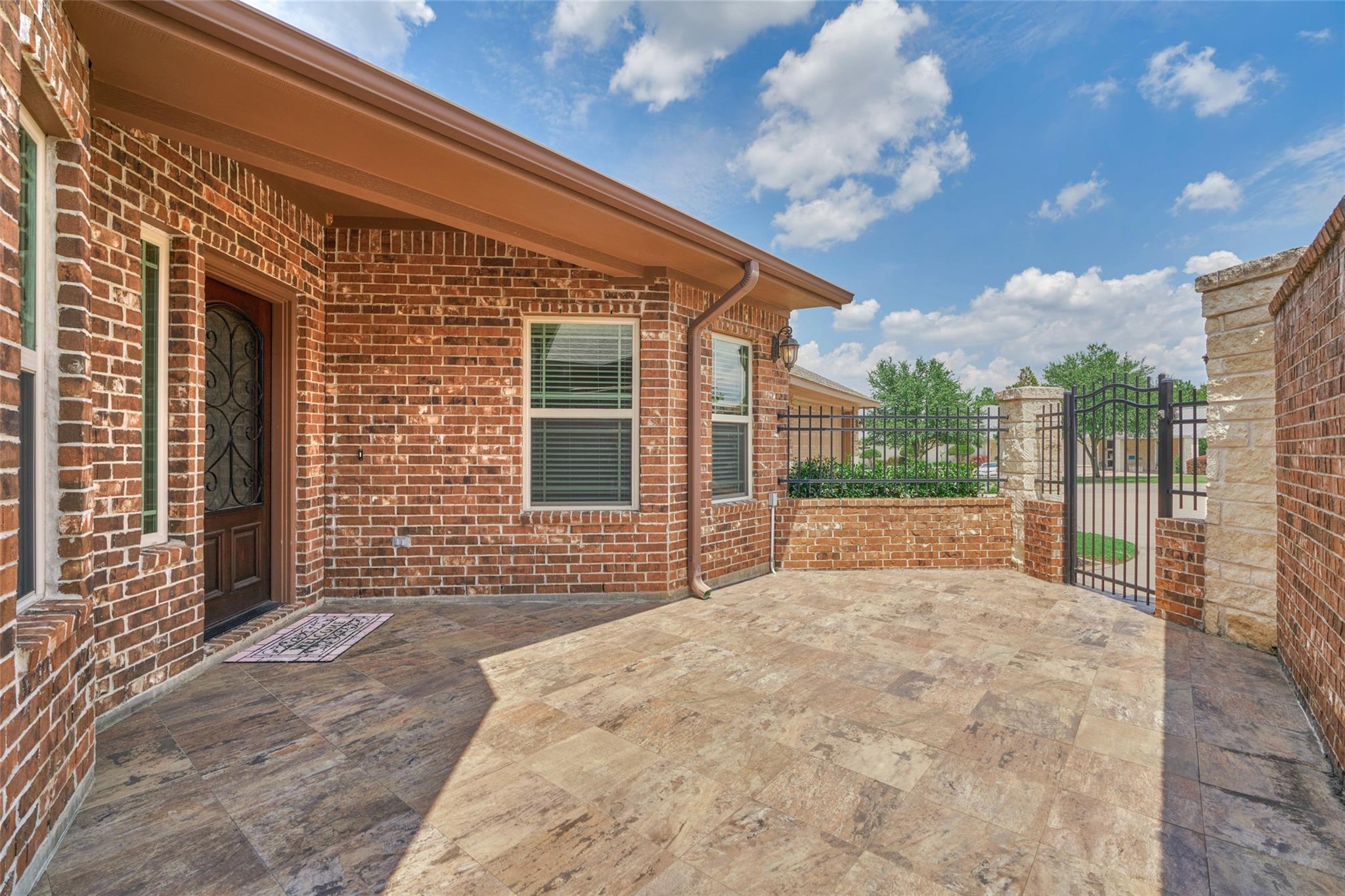 Tiled brick-house patio with a covered entry and black iron gate.