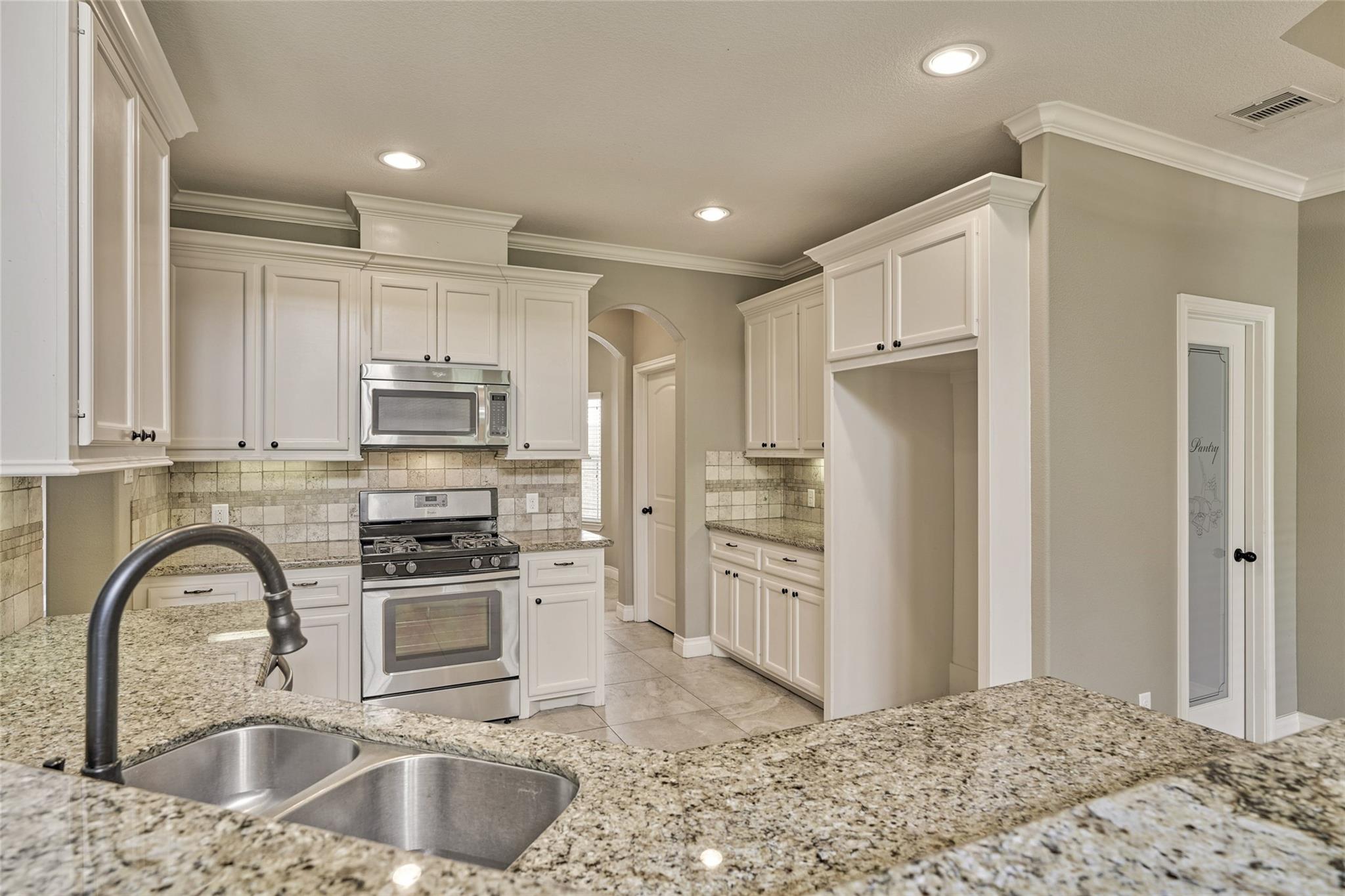 Kitchen with white cabinets, granite counters, stainless steel appliances, and a double-basin sink.