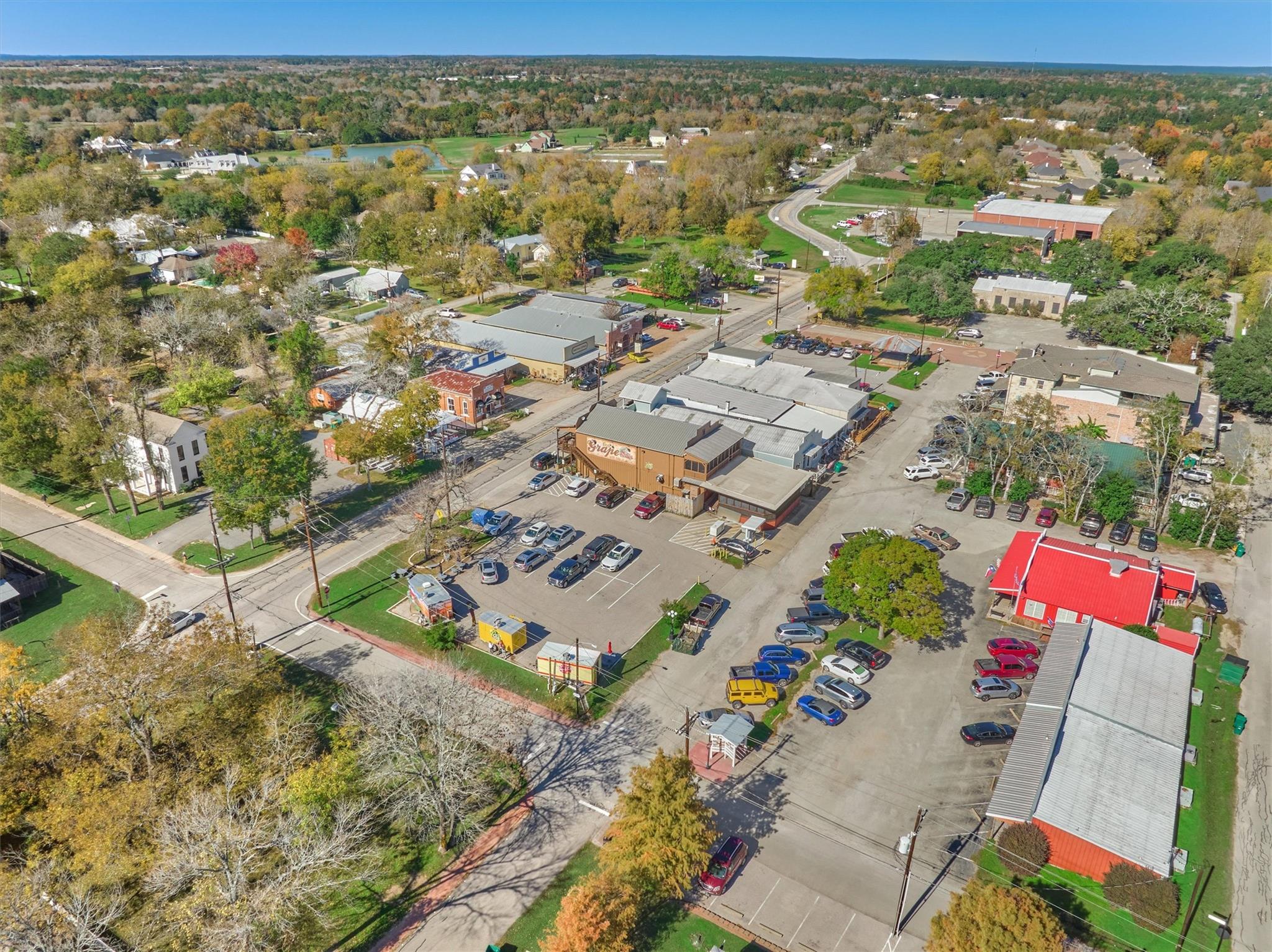 Aerial view of a commercial district with shops, parking lots, and autumn trees.