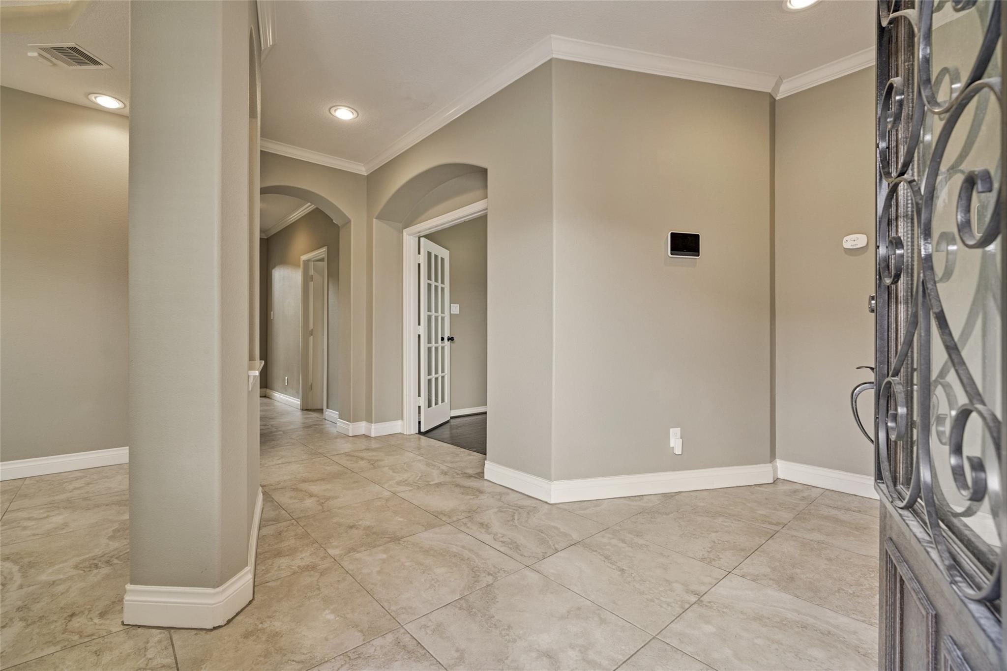 Entry foyer with tiled floors, arched openings, and an ornate iron front door.