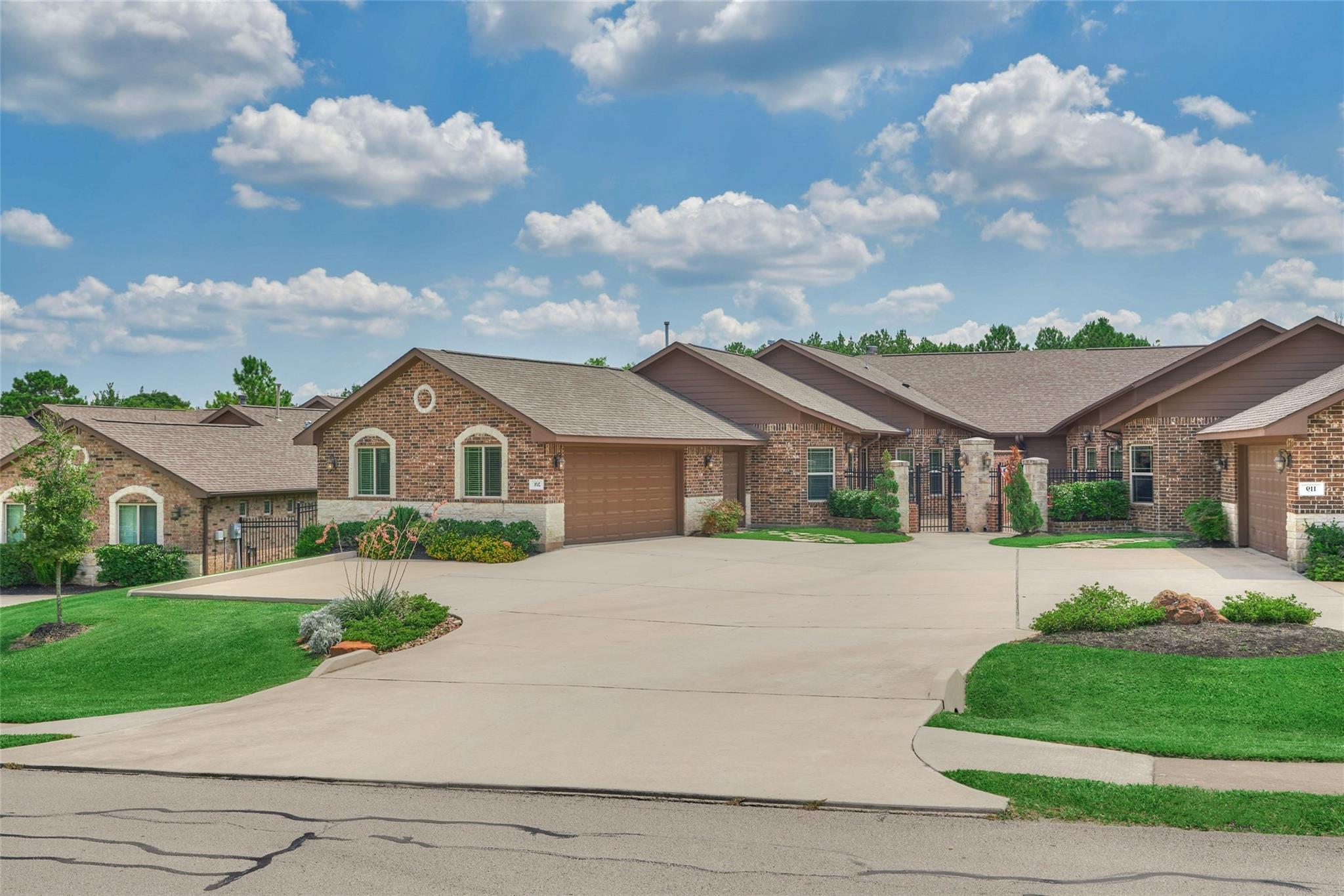 Brick home with an attached garage and broad driveway, flanked by similar homes.
