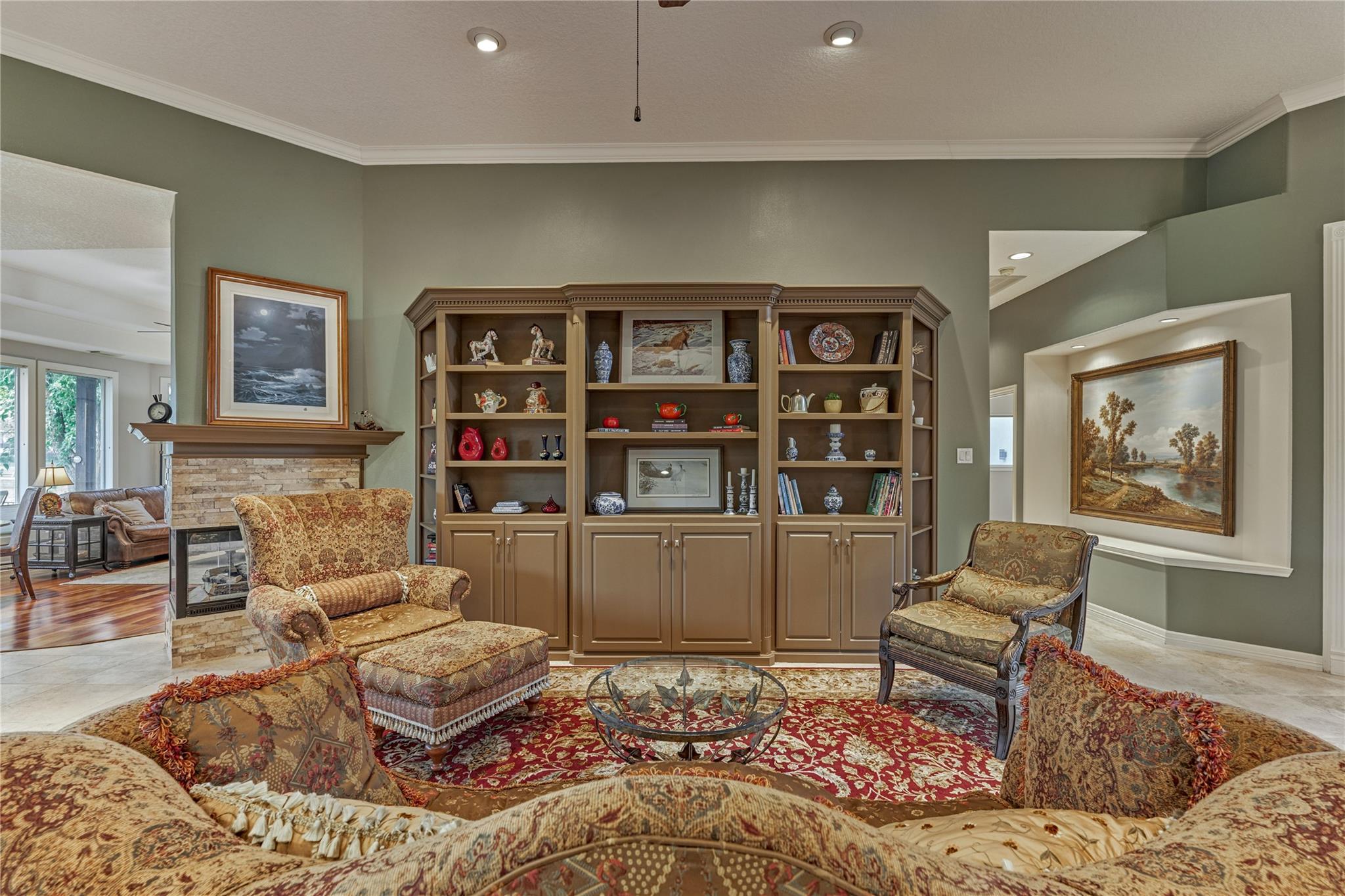 Living room with a built-in display bookcase, stone fireplace, and ornate patterned seating