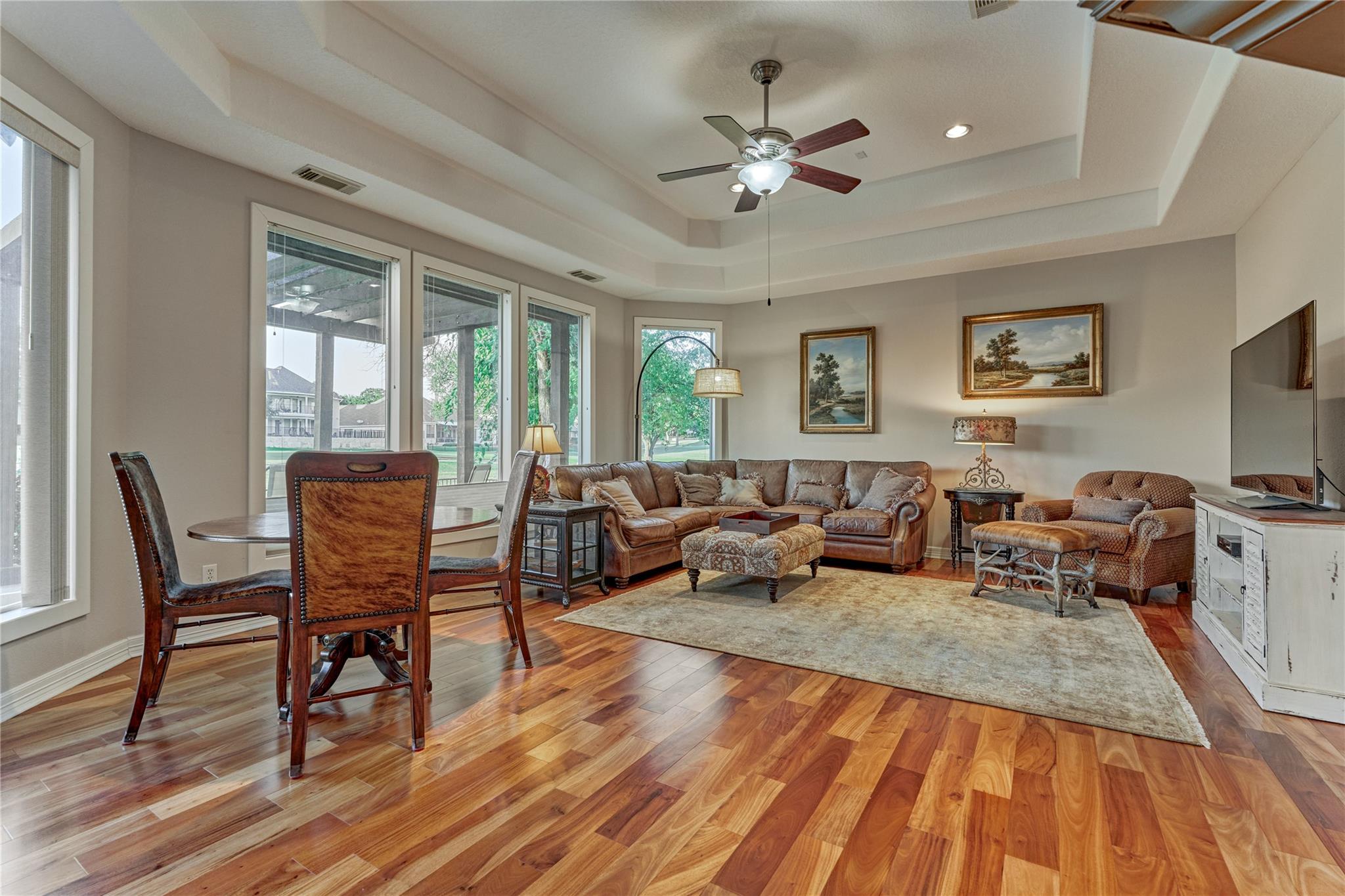 Living room with leather seating, a dining area, wood floors, and large windows.