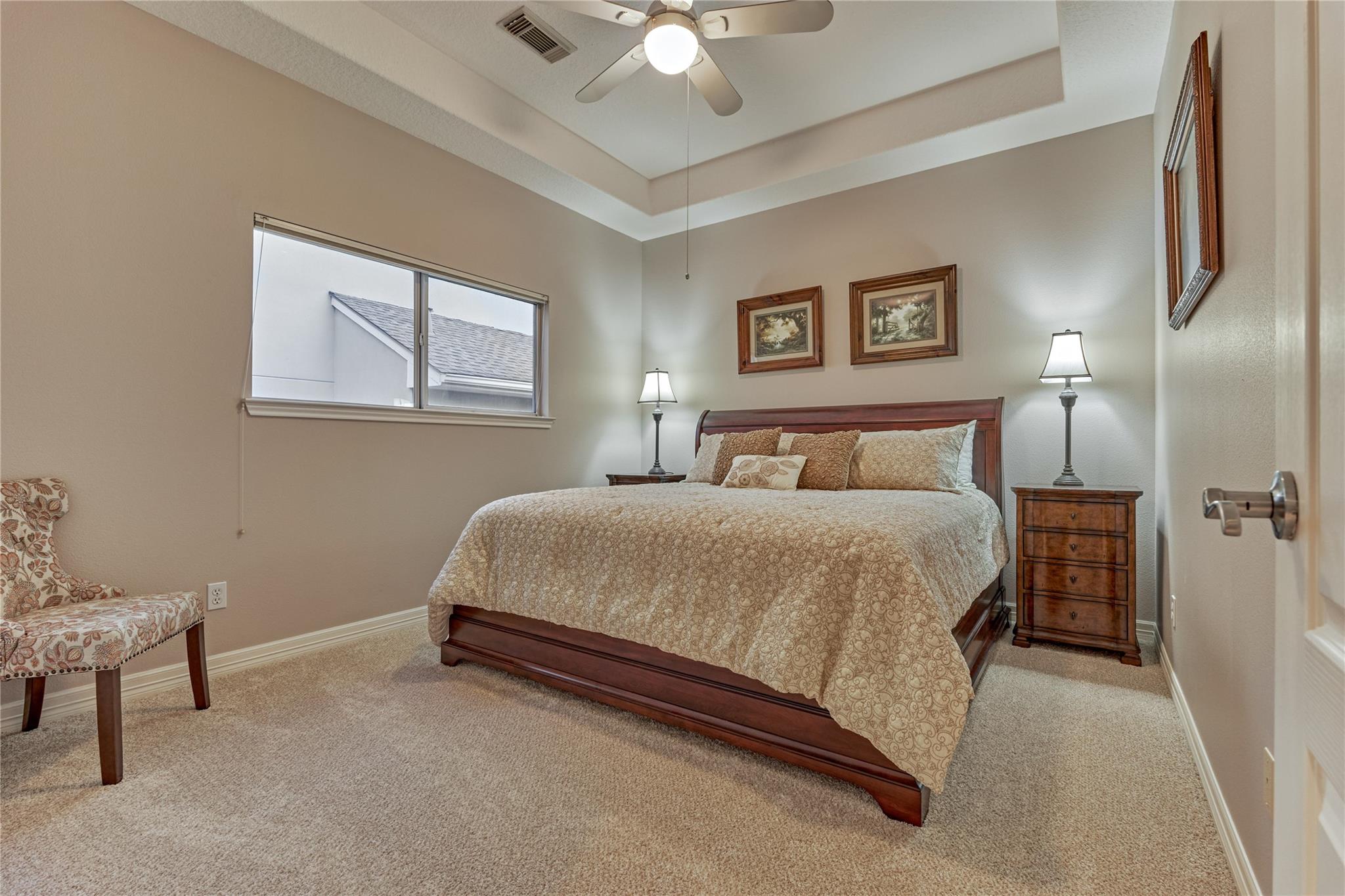Furnished bedroom with a dark wood bed, patterned bedding, carpet, and tray ceiling.
