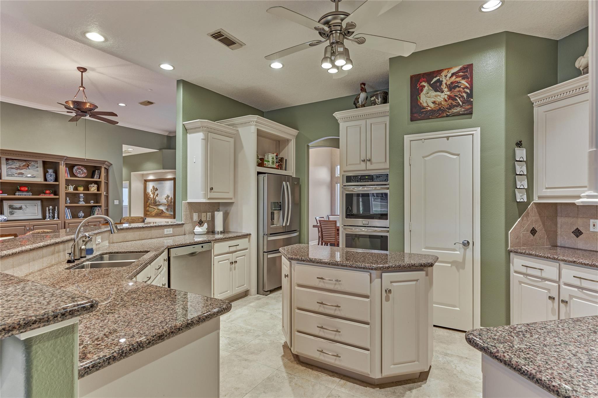 Kitchen with a granite-topped island, white cabinets, and stainless steel appliances.