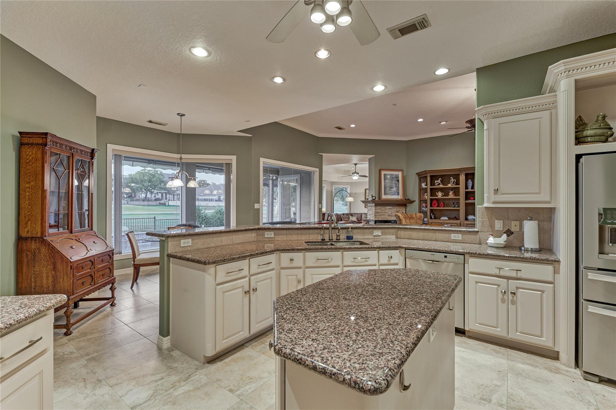 Kitchen with a granite island and windows overlooking the water, open to a living room with a fireplace.